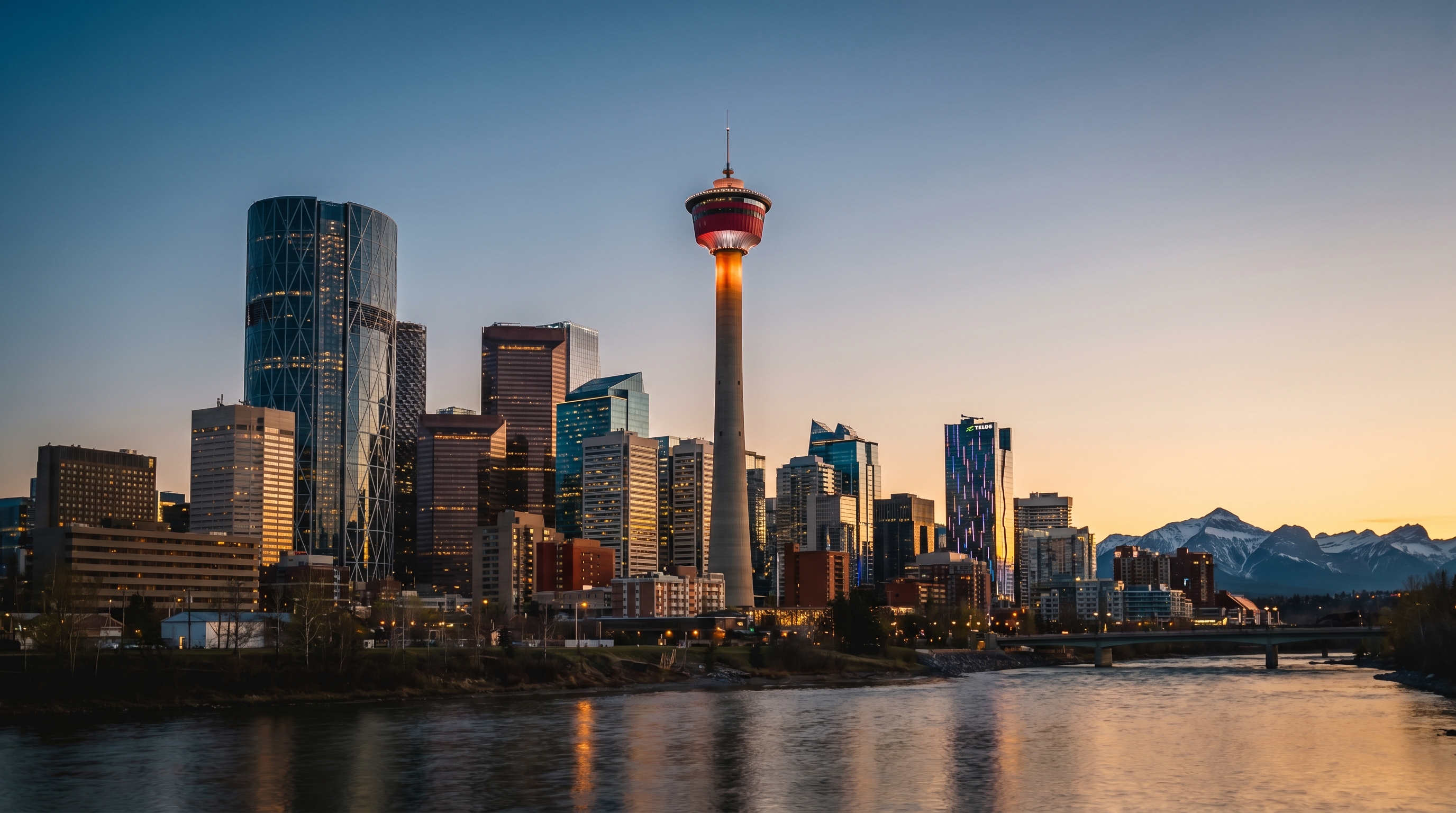 Calgary downtown skyline with Calgary Tower and Rocky Mountains at dusk